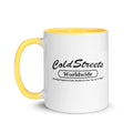 White ceramic mug with yellow handle and rim featuring Cold Streets Worldwide text