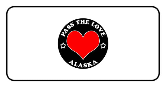 Black circular badge with PASS THE LOVE ALASKA text and red heart for paid cards clothing