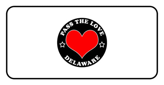 Black circular badge with red heart reading Pass The Love Delaware, surrounded by stars